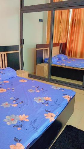 1 dormitorio con 2 camas y manta azul con flores en Timba Deluxe en Cotonú
