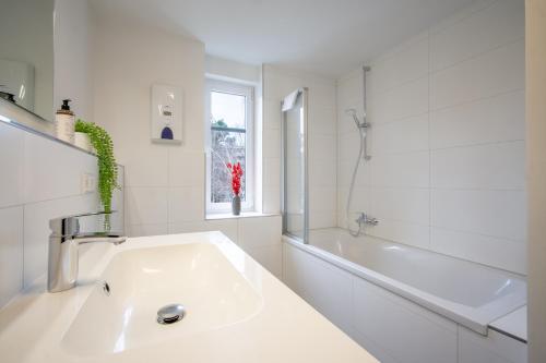 a white bathroom with a sink and a bath tub at CoView - Design Apartment - 2 Schlafzimmer - Küche - Highspeed Wlan in Dresden
