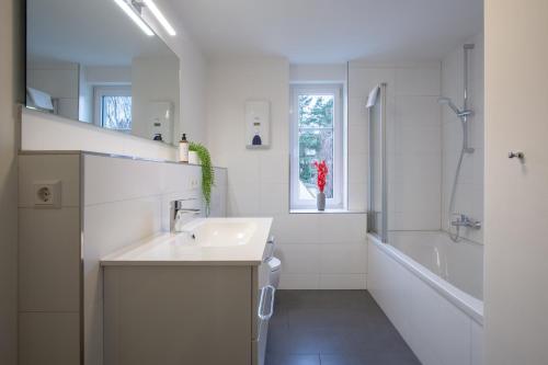 een witte badkamer met een wastafel en een bad bij CoView - ruhige Design Wohnung - 2 Schlafzimmer - voll ausgestattete Küche in Dresden