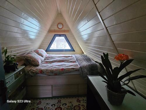 Una cama pequeña en una casa pequeña con ventana en Dom nad jeziorem en Żywiec