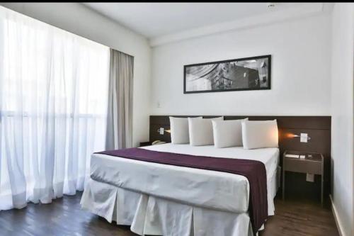 Habitación de hotel con cama grande con almohadas blancas en Apartamento Completo ao lado da lagoa da Pampulha en Belo Horizonte