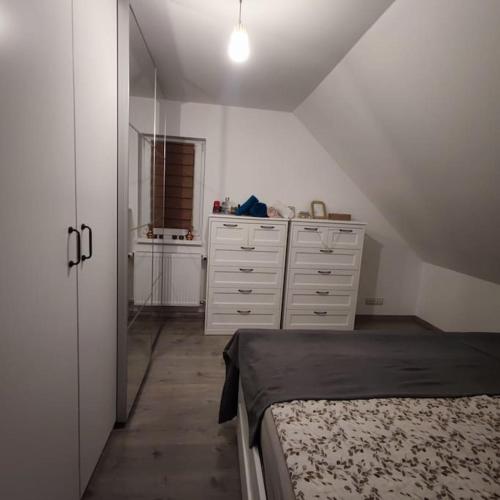 biała sypialnia z łóżkiem i komodą w obiekcie Super Family/Office Apartment in Budaörs w mieście Budaörs