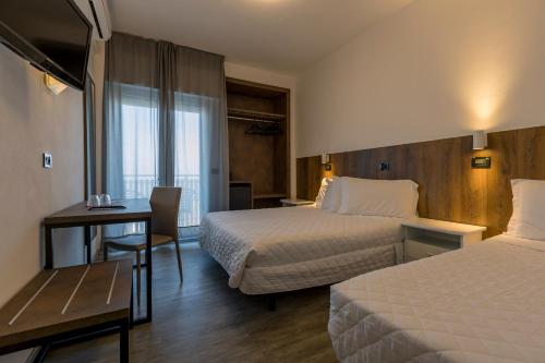 ミラノ・マリッティマにあるHotel Centraleのベッド2台とデスクが備わるホテルルームです。