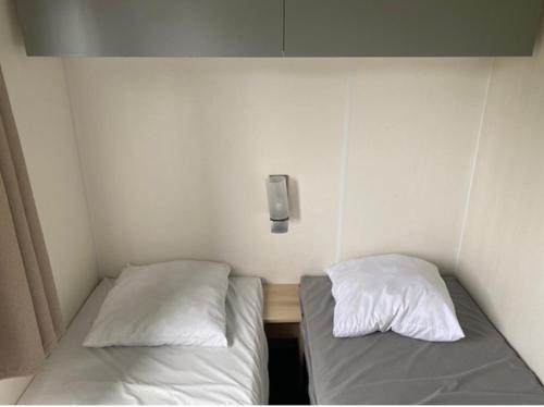Cette petite chambre comprend 2 lits et un téléphone mural. dans l'établissement Mobil home 456, à Ivry-la-Bataille