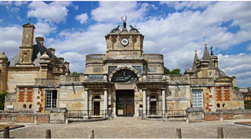 un vieux bâtiment avec une horloge à l'avant dans l'établissement Mobil home 456, à Ivry-la-Bataille