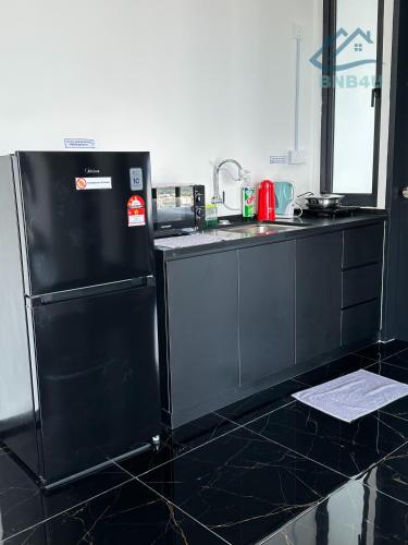 a black kitchen with a sink and a refrigerator at Urban Suites Georgetown by BNB4U in Jelutong