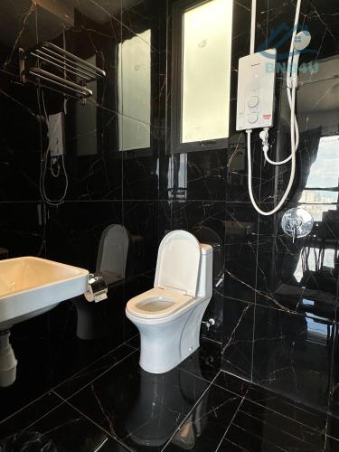 a black tiled bathroom with a toilet and a sink at Urban Suites Georgetown by BNB4U in Jelutong
