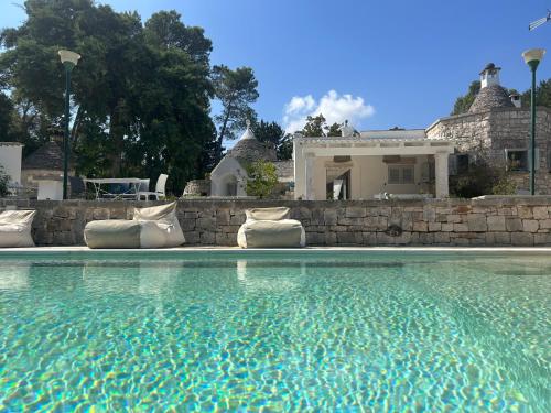 uma piscina com cadeiras e uma casa ao fundo em Il trullo di simona em Locorotondo