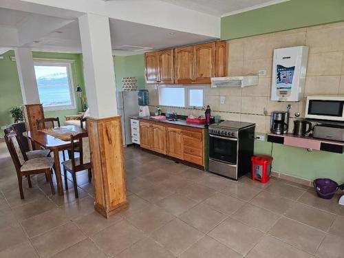 eine Küche mit Holzschränken, einem Tisch und einem Herd in der Unterkunft Departamento en zona residencial in Ushuaia