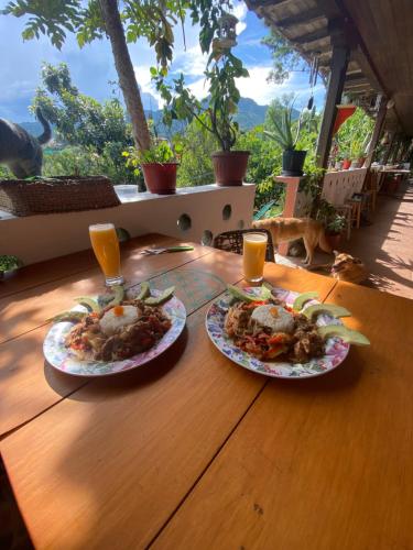 two plates of food on a wooden table with drinks at Matilda Ec in Vilcabamba