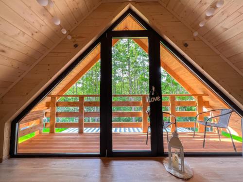 a window in a cabin with a view of a deck at Las Lorien - wynajem domków letniskowych in Roczyny