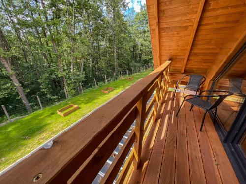a large deck with two chairs and a table on it at Las Lorien - wynajem domków letniskowych in Roczyny