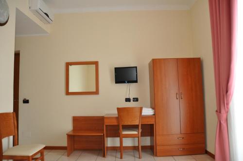 a room with a table and a cabinet and a television at Hotel Belforte in Varese