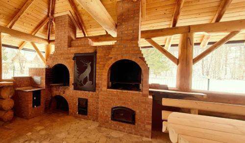 a brick fireplace in a room with a wooden ceiling at Pensiunea Poiana Cerbului in Tarcău-Gheuca