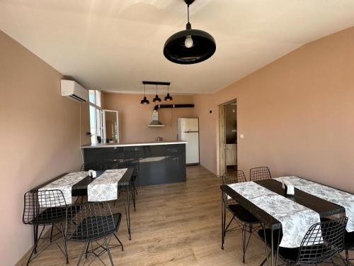 a dining room with tables and chairs and a kitchen at Hotel Tatul in Momchilgrad