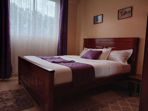 ein großes Bett in einem Schlafzimmer mit Fenster in der Unterkunft J's Nest in Kericho