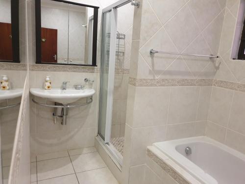 biała łazienka z umywalką i prysznicem w obiekcie Grace Avenue Townhouse w mieście Port Edward