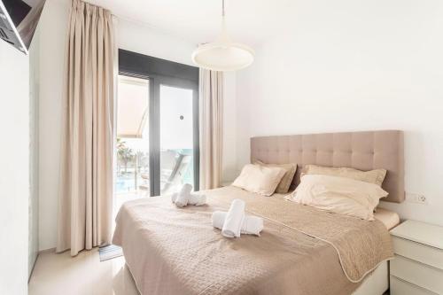 a bedroom with a bed with two white towels on it at Relax, vacaciones y lujo a 15 metros del mar in Arenales del Sol