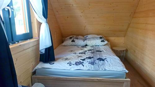 a bed in a wooden cabin with a window at Las Lorien - wynajem domków letniskowych in Roczyny