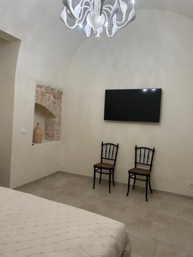 1 dormitorio con 2 sillas y TV de pantalla plana en Le segrete del Notaio en Conversano