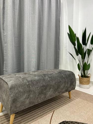 a grey velvet bench in a room with a curtain at Havengate Homestay in Butterworth