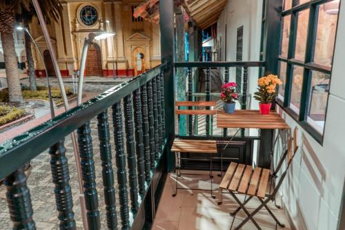 uma varanda com duas cadeiras e uma mesa com flores em Genazzano Hotel Boutique em Jenesano