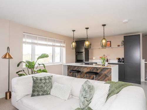 a living room with a white couch and a kitchen at The Hayloft in Amlwch