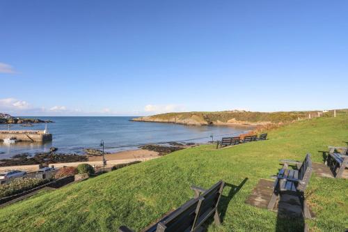 a group of benches sitting on the grass near the water at The Hayloft in Amlwch