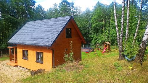 a small house in a field with a playground at Las Lorien - wynajem domków letniskowych in Roczyny