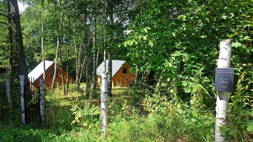 a cabin in the woods with a sign in the foreground at Las Lorien - wynajem domków letniskowych in Roczyny