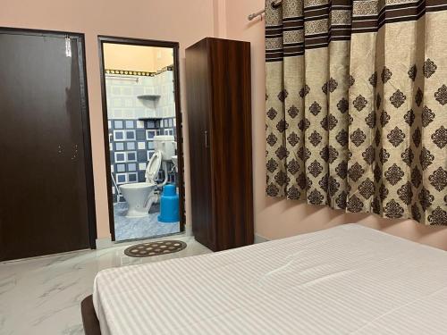 een slaapkamer met een bed en een badkamer met een toilet bij Sumangal Homestay in kolkata