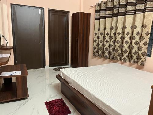 een slaapkamer met een bed, een tafel en een raam bij Sumangal Homestay in kolkata