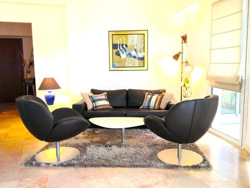 - un salon avec un canapé noir et deux chaises dans l'établissement Cannes Croisette Two bedrooms, à Cannes
