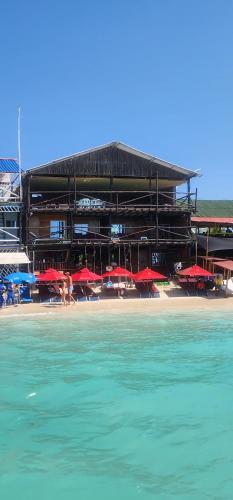 a beach with a building with red umbrellas and the water at Ecohotelhector in Playa Blanca