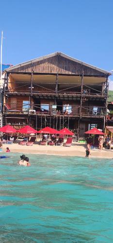 a beach with red umbrellas and people in the water at Ecohotelhector in Playa Blanca
