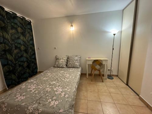 Dormitorio pequeño con cama y mesa en Location studio meublé 49€/nuit, en Sainte-Clotilde