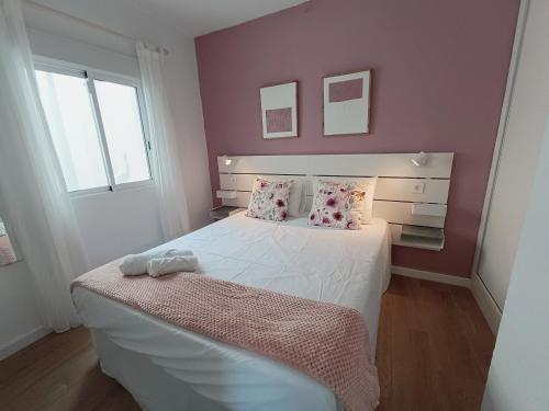 - une chambre avec un lit blanc aux murs roses dans l'établissement Coqueto apto en centro histórico, à Marbella