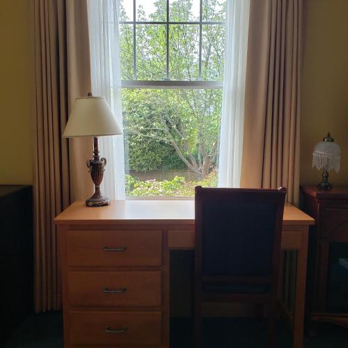 a desk with a lamp in front of a window at James Bay Inn Hotel, Suites & Cottage in Victoria