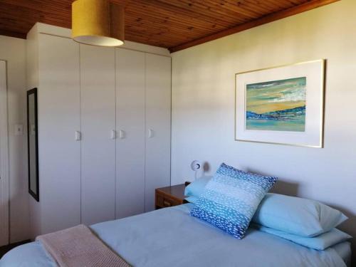 a bedroom with a bed with a blue pillow at Enchanting cottage, Little Arniston Kaysers Beach in Kayserʼs Beach