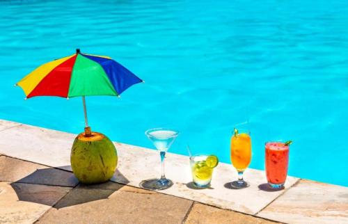 - un groupe de quatre boissons assis à côté d'une piscine dans l'établissement Beira-Mar flat 310 Ponta Negra Beach, à Natal