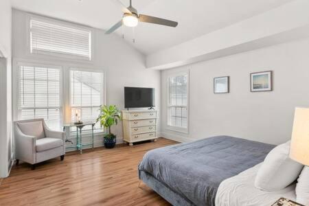 a bedroom with a bed and a tv and a chair at Timeless Elegance Historic NOLA Haven 2BD in New Orleans