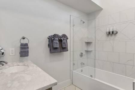 a white bathroom with a shower and a sink at Timeless Elegance Historic NOLA Haven 2BD in New Orleans