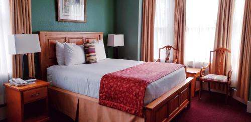 a bedroom with a large bed with a red blanket at James Bay Inn Hotel, Suites & Cottage in Victoria