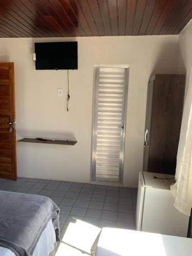 1 dormitorio con 1 cama y TV en la pared en Pousada Caminho do Paraiso, en Maragogi