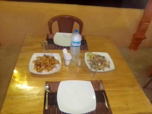 a table with two plates of food and a bottle of water at Dolphin Village in Kalpitiya