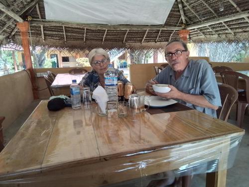 a man and a woman sitting at a wooden table at Dolphin Village in Kalpitiya