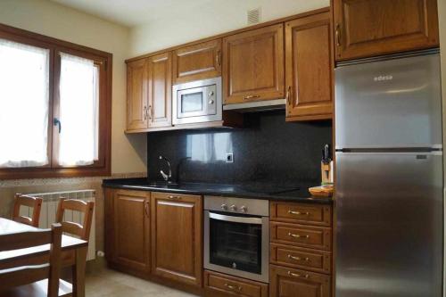 a kitchen with wooden cabinets and a stainless steel refrigerator at Amalur Irati in Ezcároz