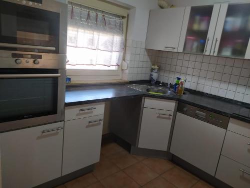 eine Küche mit weißen Schränken und einer schwarzen Arbeitsplatte in der Unterkunft Room in shared apartment in Friedrichshafen