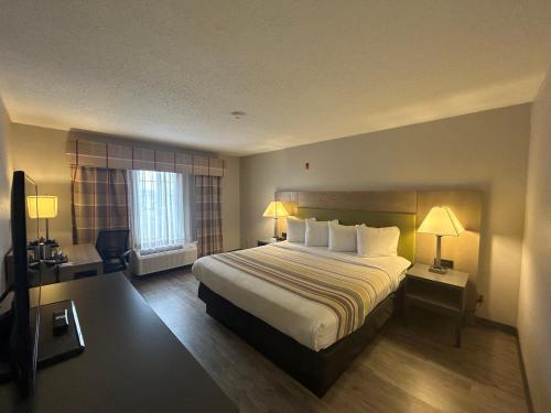 um quarto de hotel com uma cama grande e uma janela em Country Inn & Suites by Radisson, Grand Rapids Airport, MI em Grand Rapids