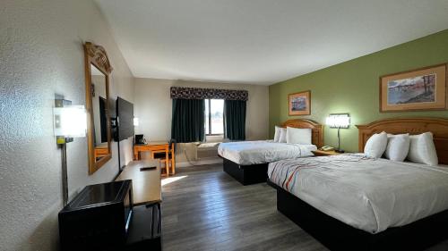 a hotel room with two beds and a television at Regency Inn and Suites in Stilwell